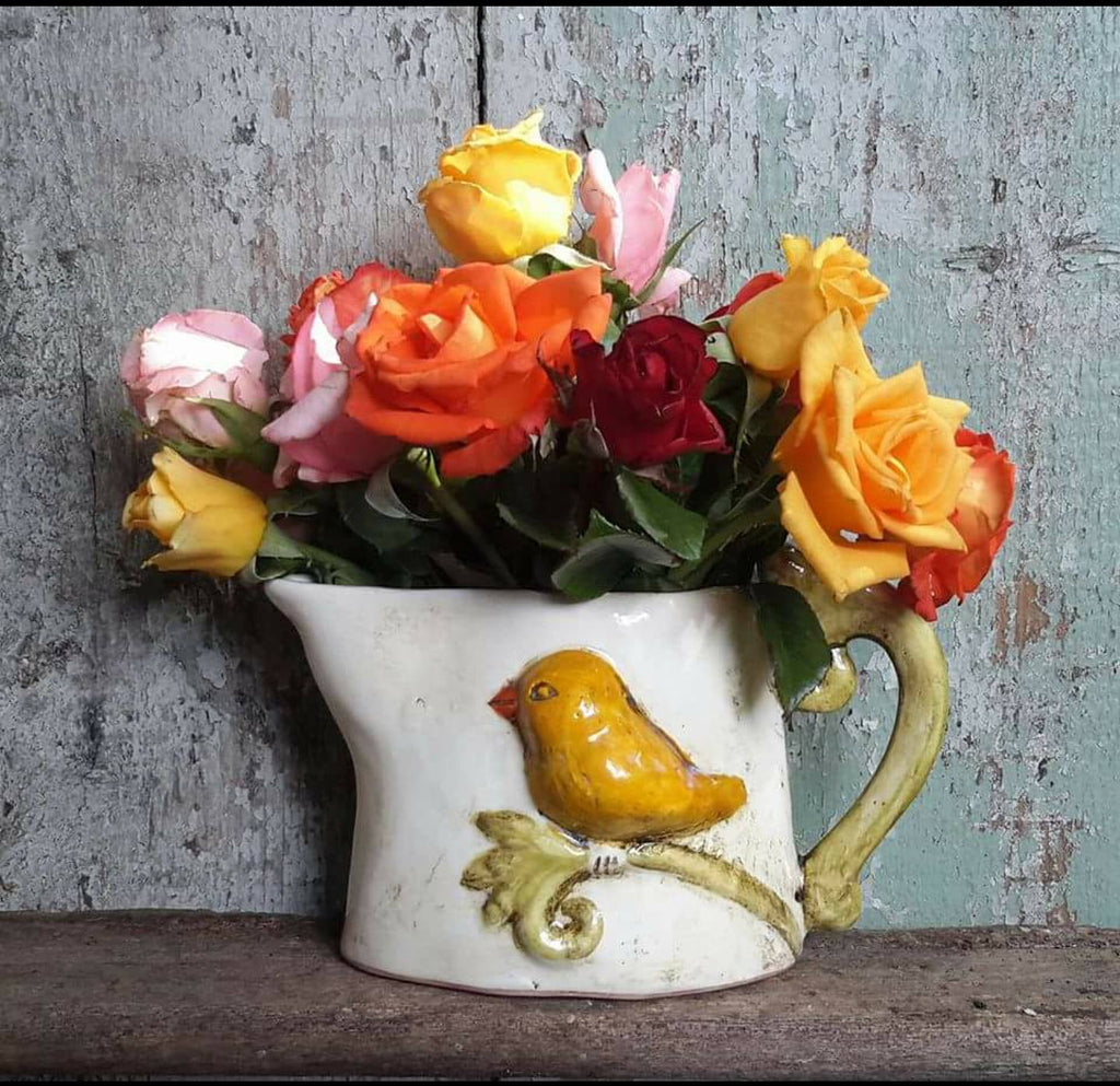 Jug shape vase with yellow bird design, also with roses in the vase