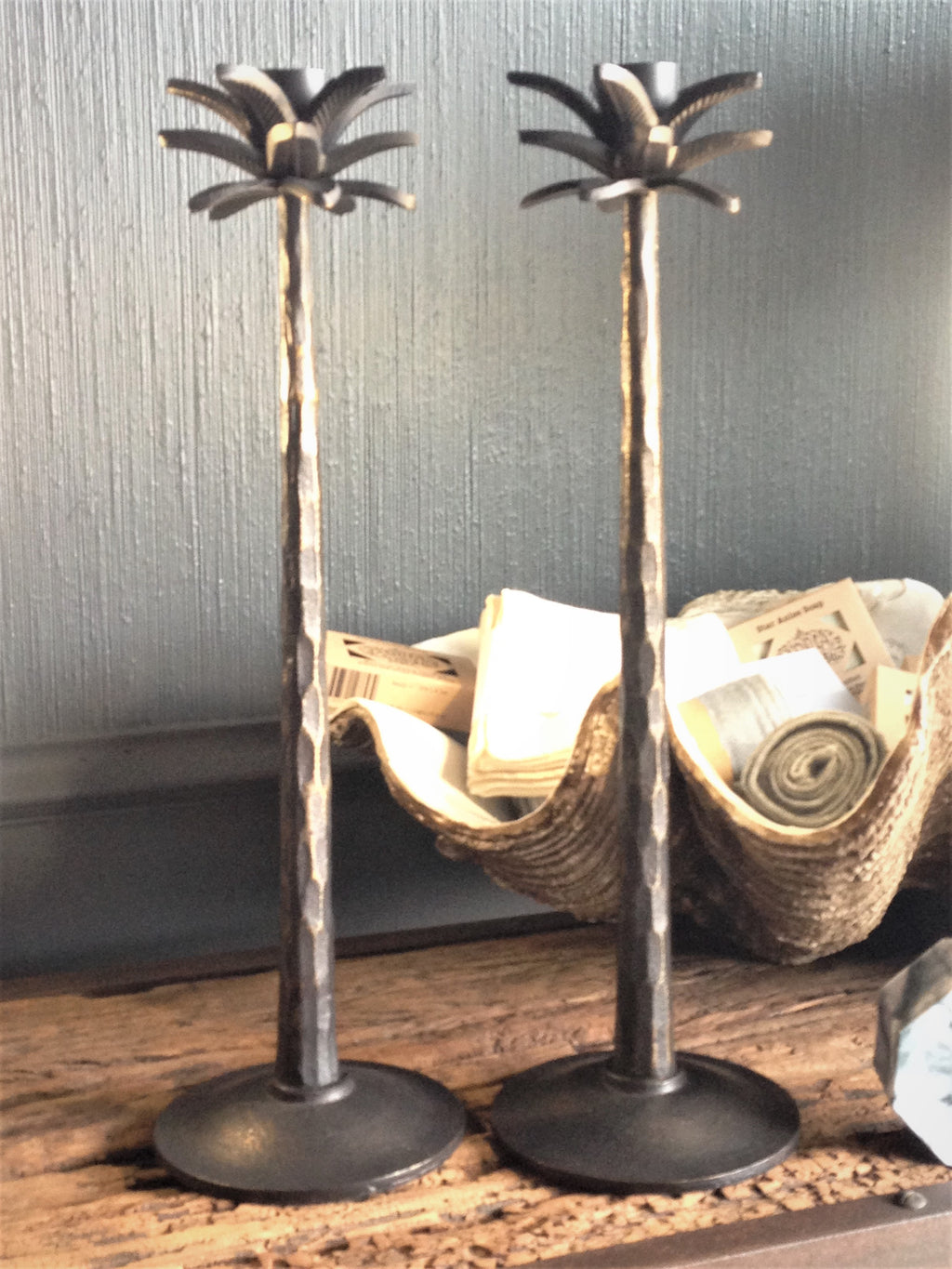 Two upright candlesticks with palm leaf design at the top.