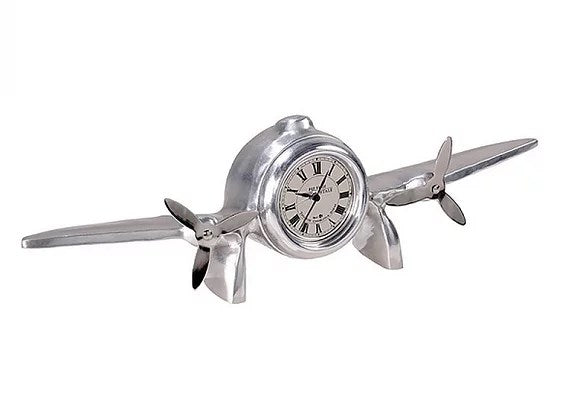Silver coloured clock in shape of aeroplane with wings and propellers. Clock is in aircraft body. Dial has Roman Numerals.