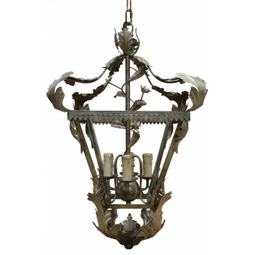 Ornate metal chandelier with leaf design and four candle bulbs.